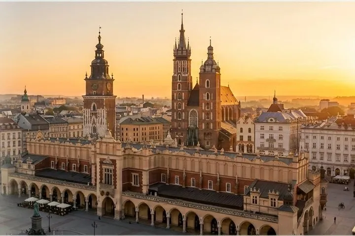 Kraków Main Square at sunrise: the Cloth Hall arcades, Town Hall Tower and St. Mary’s Basilica against an amber sky